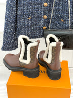Two brown Louis Vuitton ankle boots with white sherpa cuffs and monogram detailing