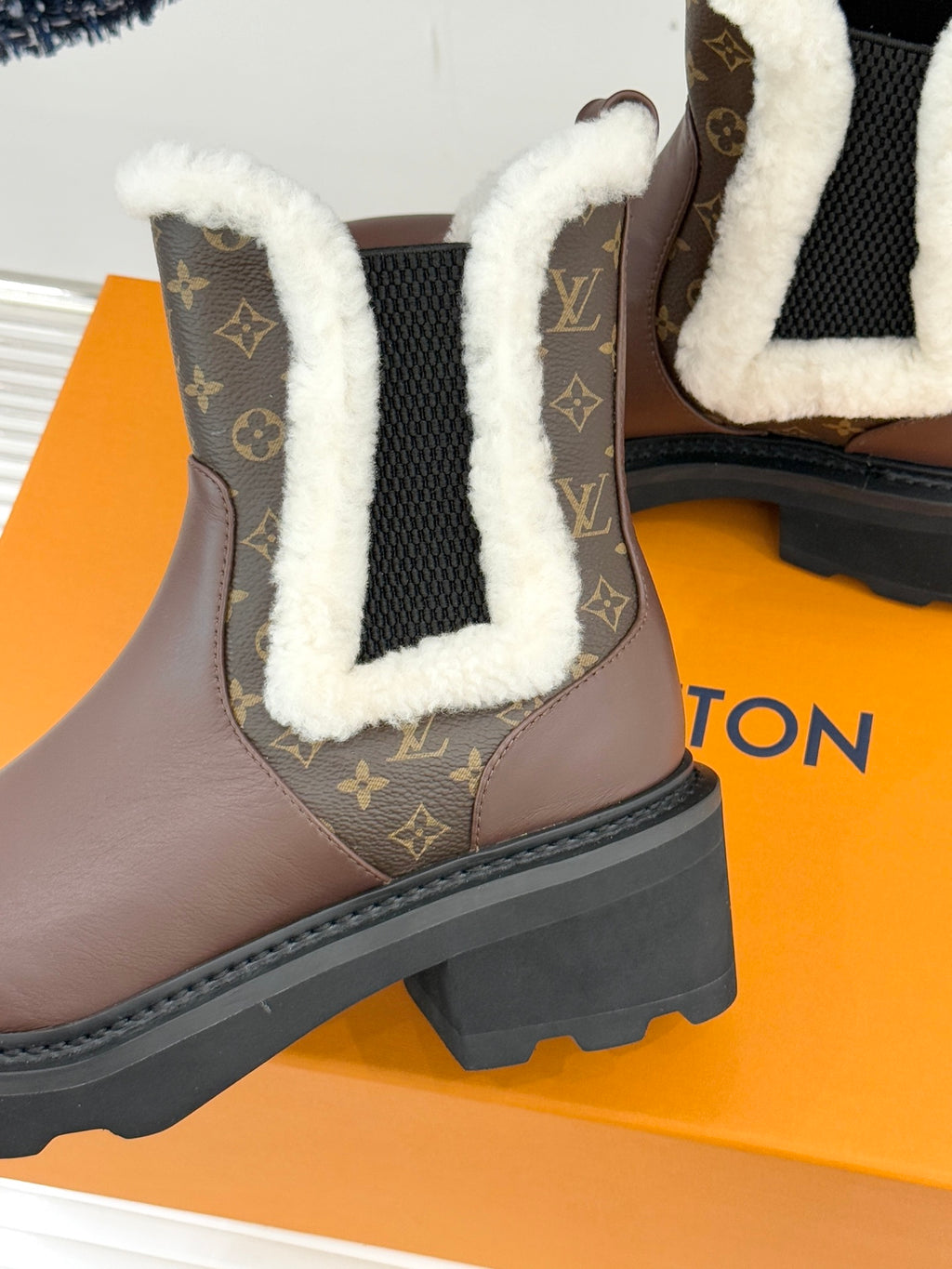 Close-up of brown Louis Vuitton ankle boot with monogram side panel and white sherpa trim
