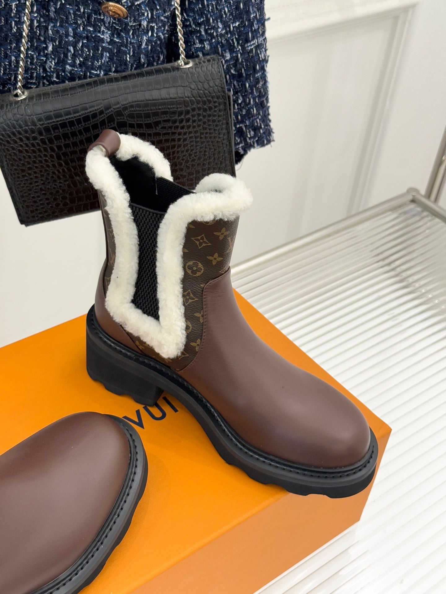 Brown Louis Vuitton ankle boot with white sherpa collar and dark rubber sole