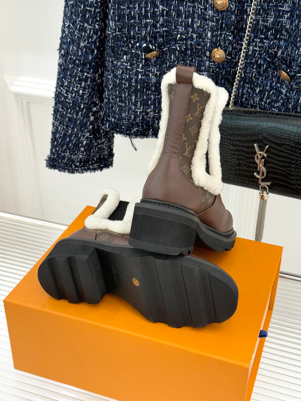 Back view of brown Louis Vuitton ladies ankle boots on orange box with lug soles