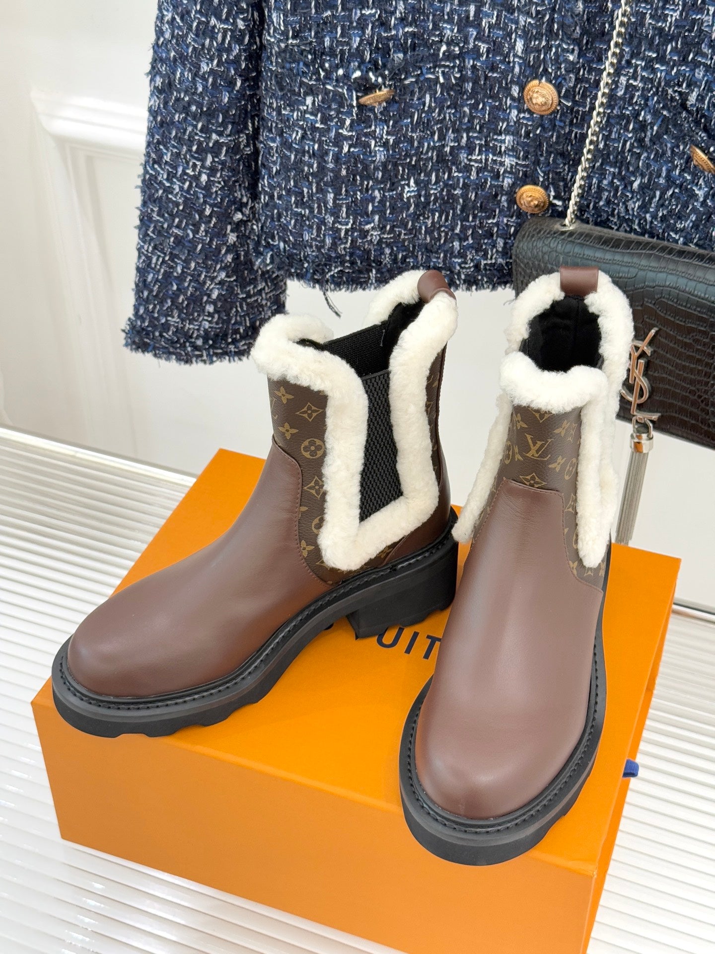 Pair of brown Louis Vuitton ankle boots with white sherpa trim and monogram inserts