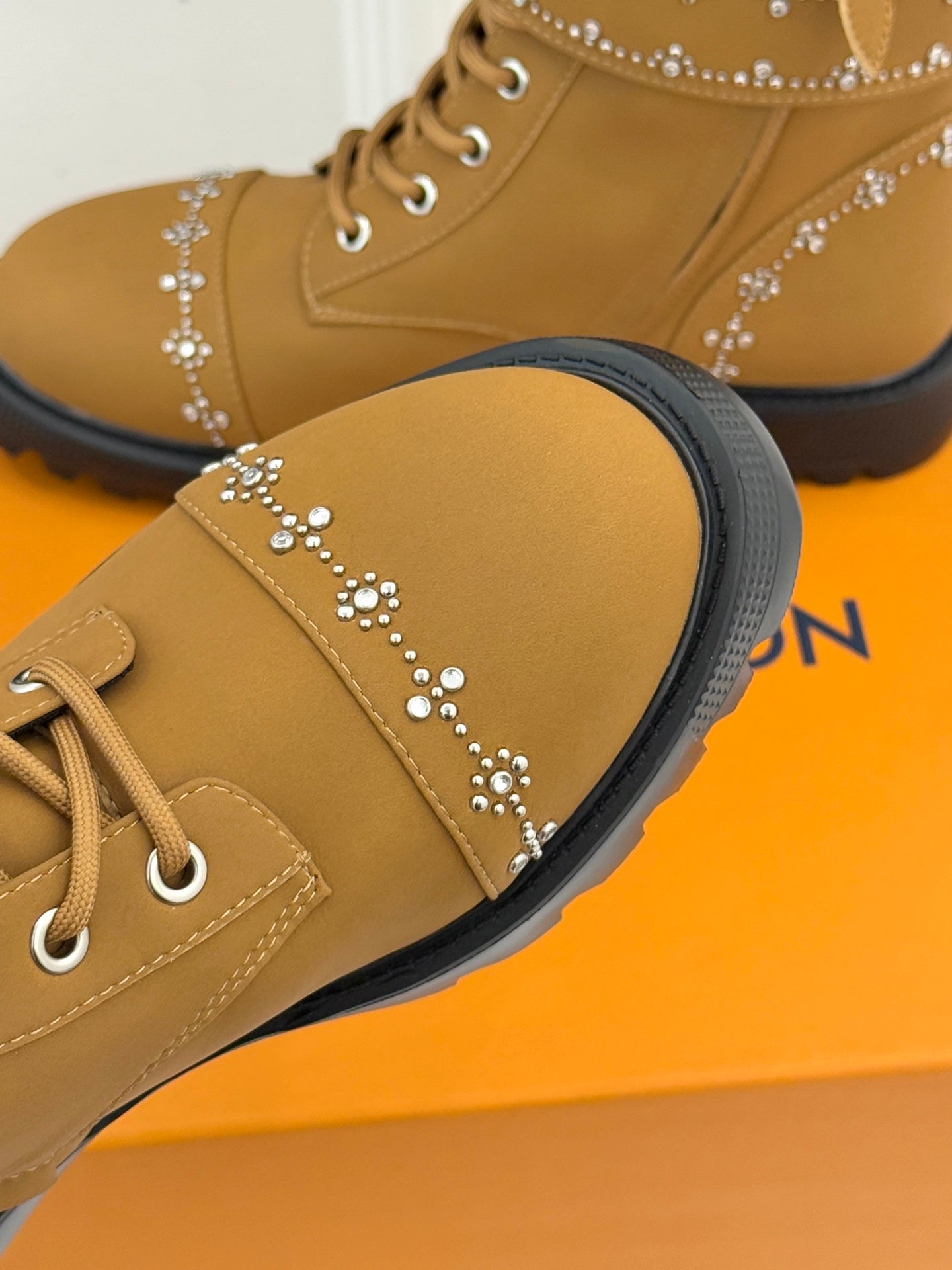 Tan high-top boot with gold studded side line and ribbed black sole