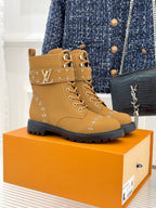 Tan high-top lace-up boots with gold studded trim and chunky rubber sole