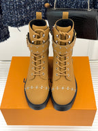Pair of tan high-top lace-up boots with gold studded straps and chunky tread sole