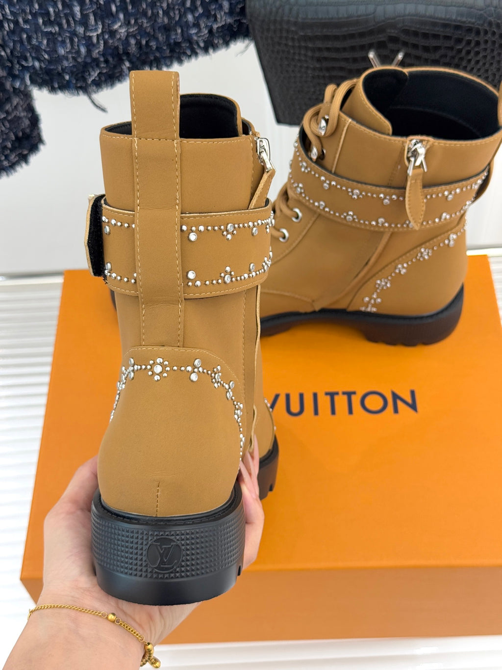 Tan high-top lace-up boots with ankle cross-strap and gold studded trim