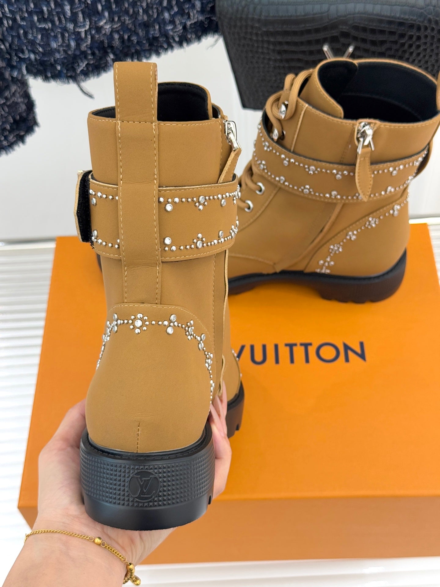 Tan high-top lace-up boots with ankle cross-strap and gold studded trim