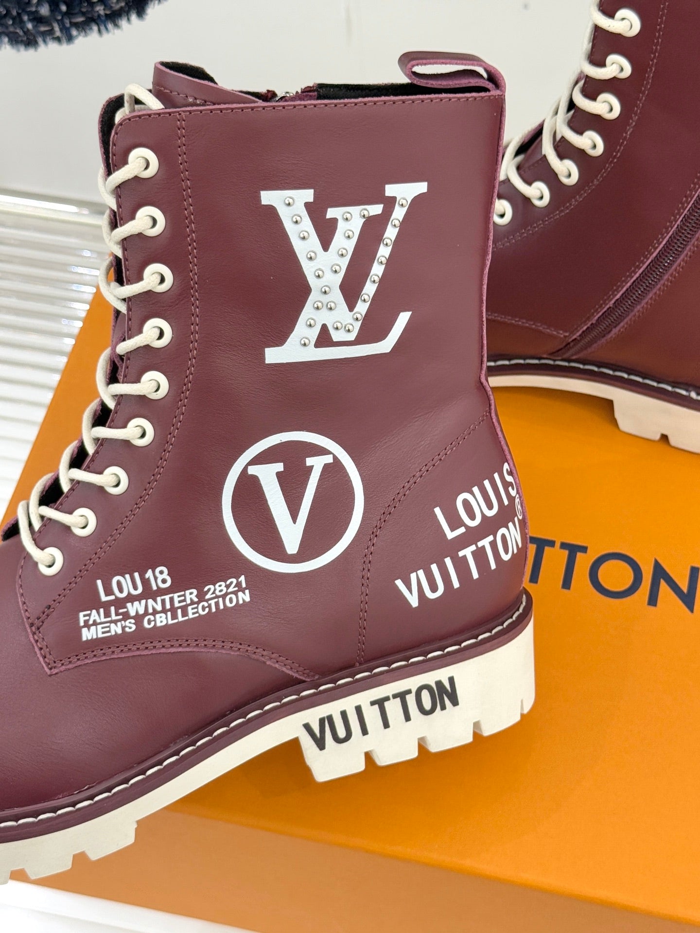 Burgundy Louis Vuitton lace-up ankle boot close-up with large LV and V logos, white sole