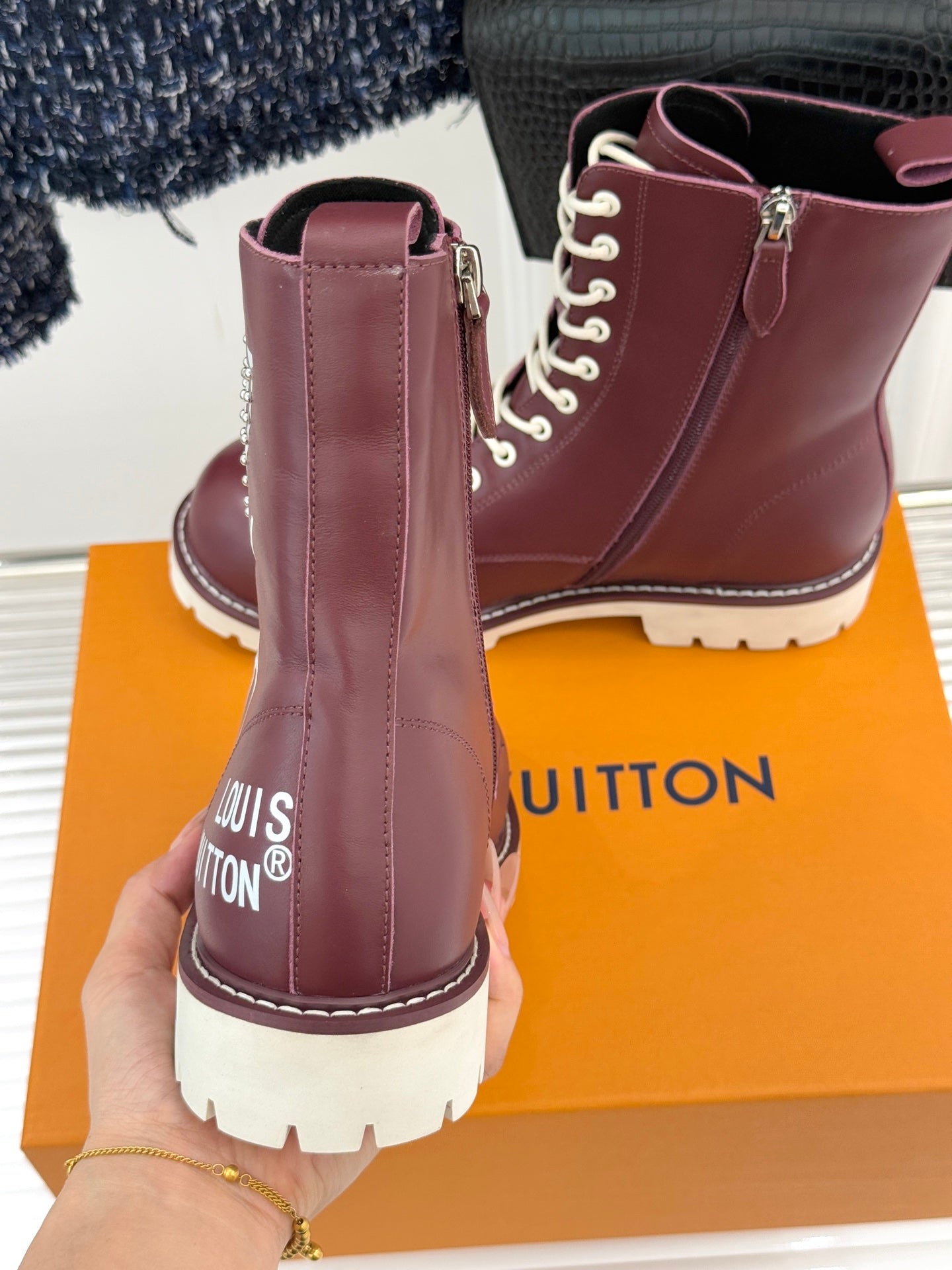 Burgundy Louis Vuitton lace-up ankle boots with side zippers, showing heel and tread sole