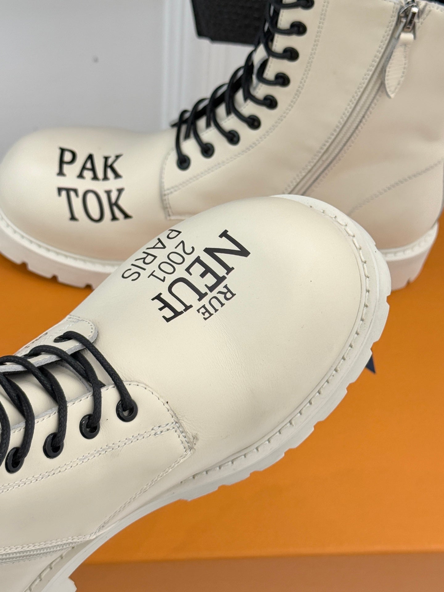 Cream ankle boot toe and side close-up with black lace eyelets and logo print