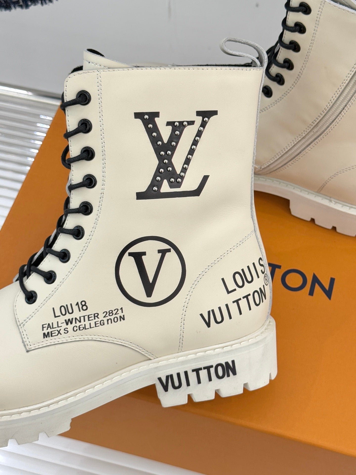 Cream ankle boot close-up with Louis Vuitton logos, black laces, and padded collar