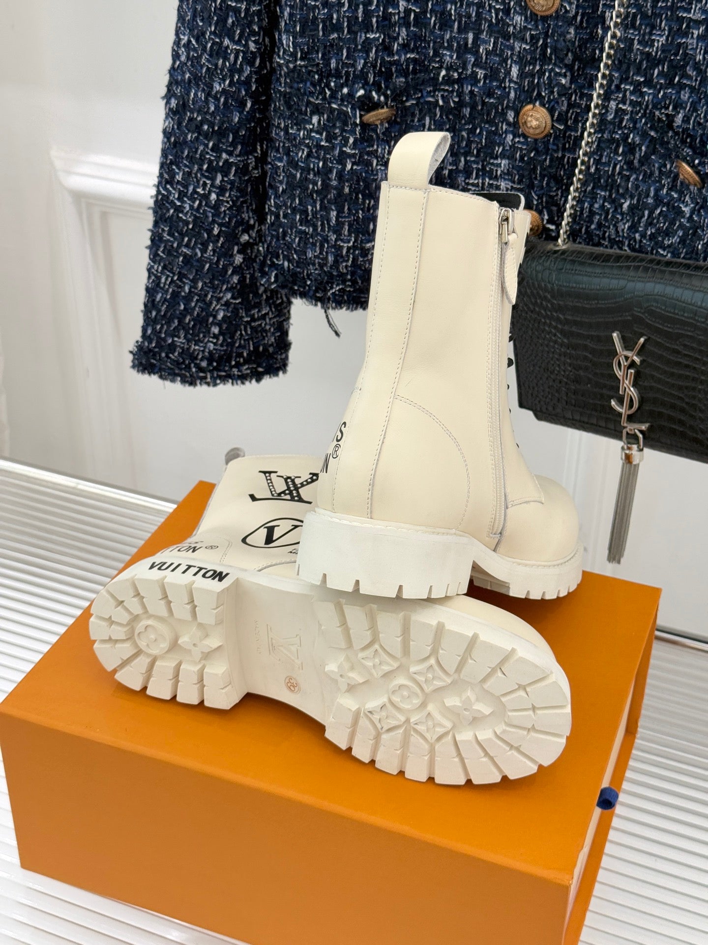 Cream ankle boots with chunky sole tread and side logo, paired on an orange box