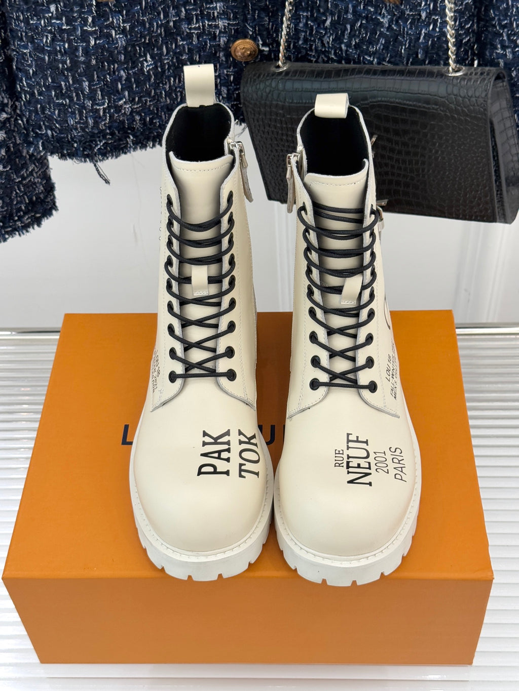 Cream lace-up ankle boots with black laces, thick tread sole, and side logo print