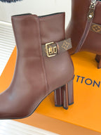 Brown leather ankle boot with side zipper, gold buckle logo, and block heel