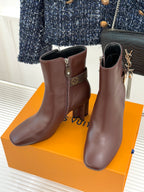 Pair of brown heeled ankle boots with side zipper and monogram patch