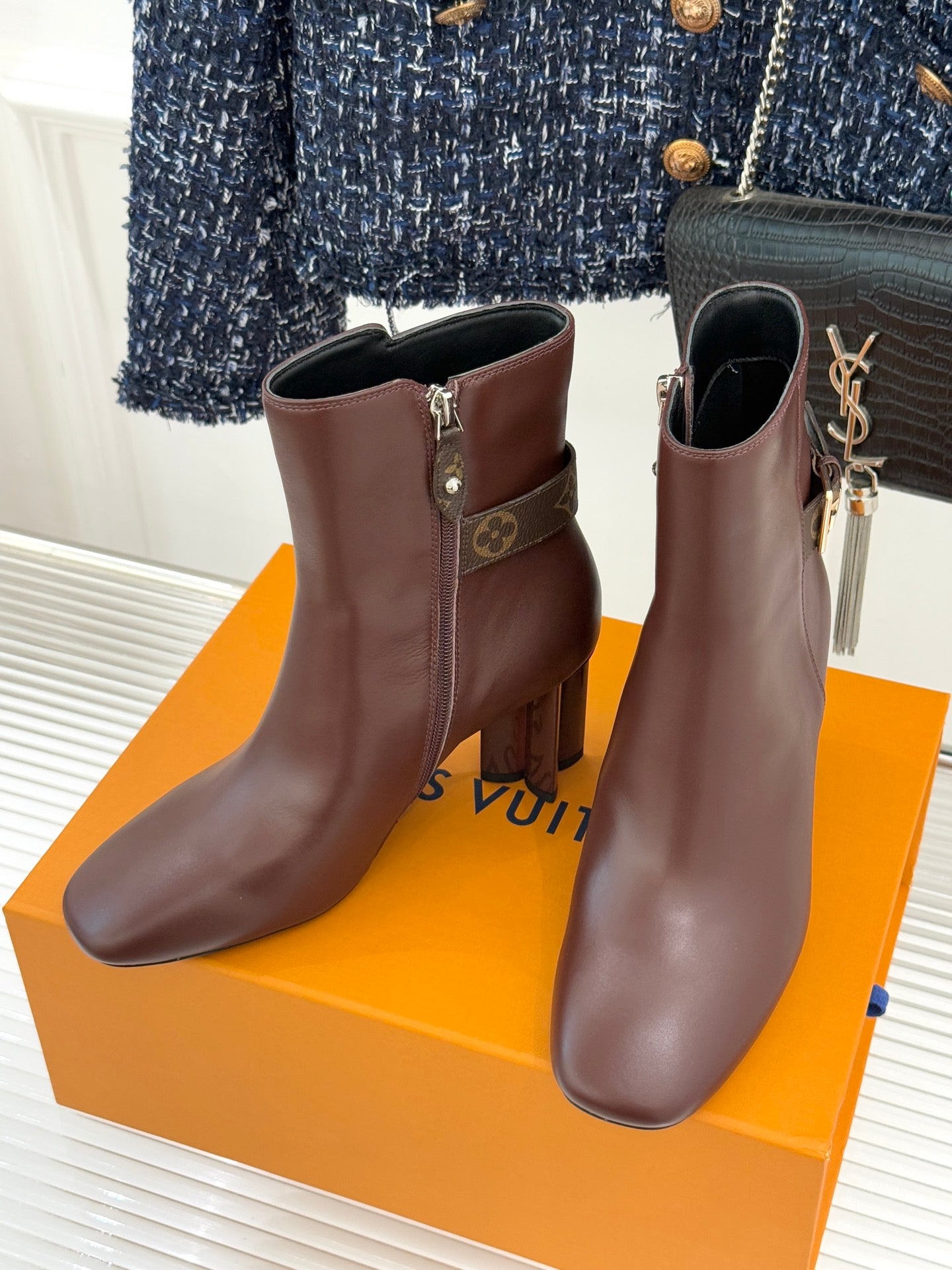 Pair of brown heeled ankle boots with side zipper and monogram patch