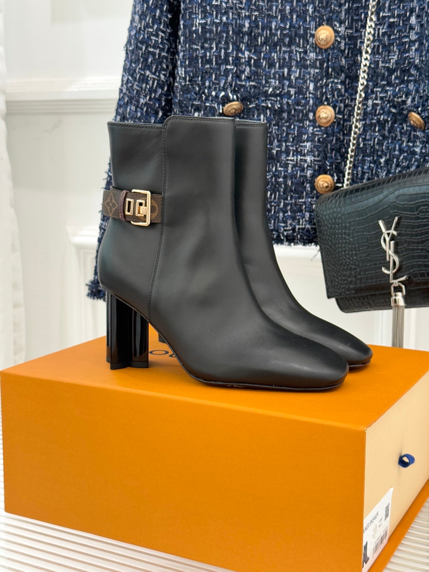 Womens ankle boots in dark leather with block heel and side zip, logo buckle strap.
