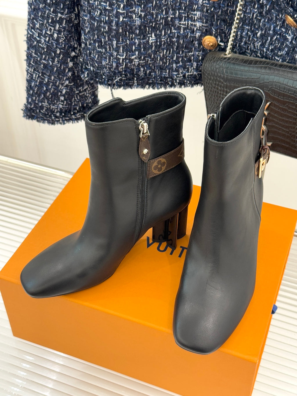 Pair of womens dark leather ankle boots with side zips and block heels, logo strap detailing.