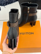 Womens dark leather ankle boots with side zips, logo strap, and tall block heels.