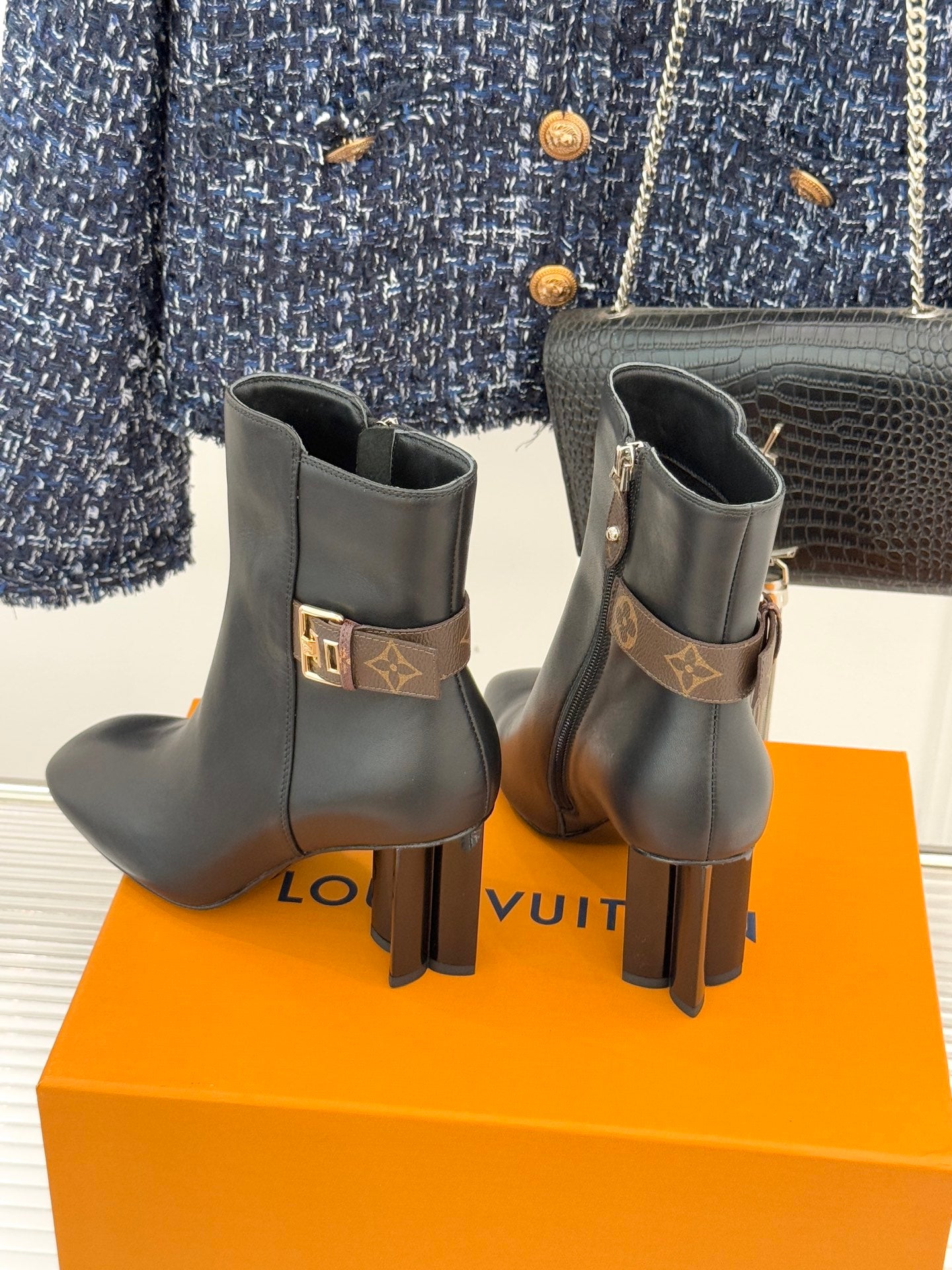 Womens dark leather ankle boots with block heels, side zips, and logo buckle strap.