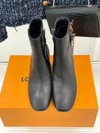 Womens dark leather ankle boots with side zips, tall block heels, and logo strap.