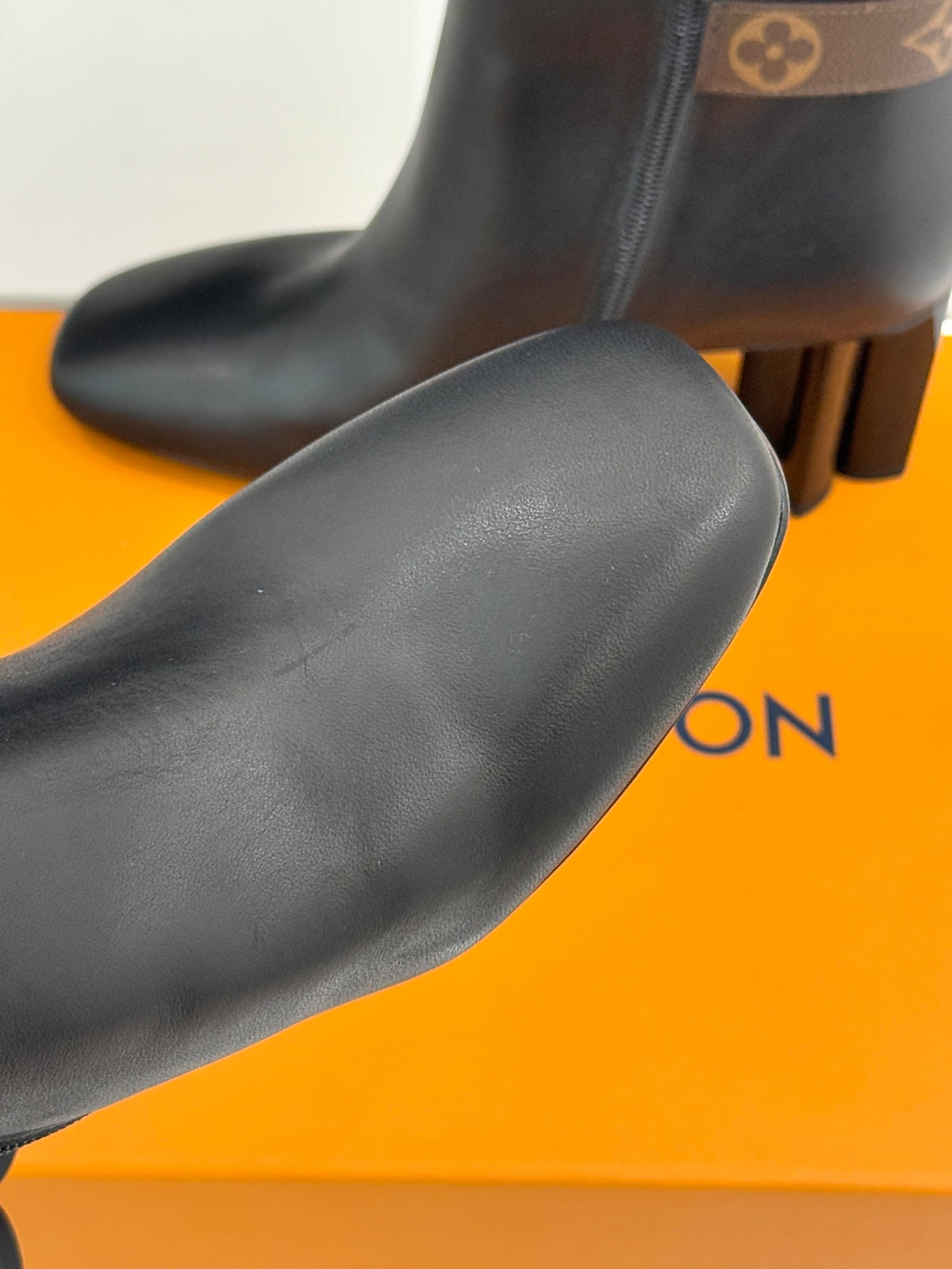 Womens dark leather ankle boot toe and upper with smooth finish, block heel visible.