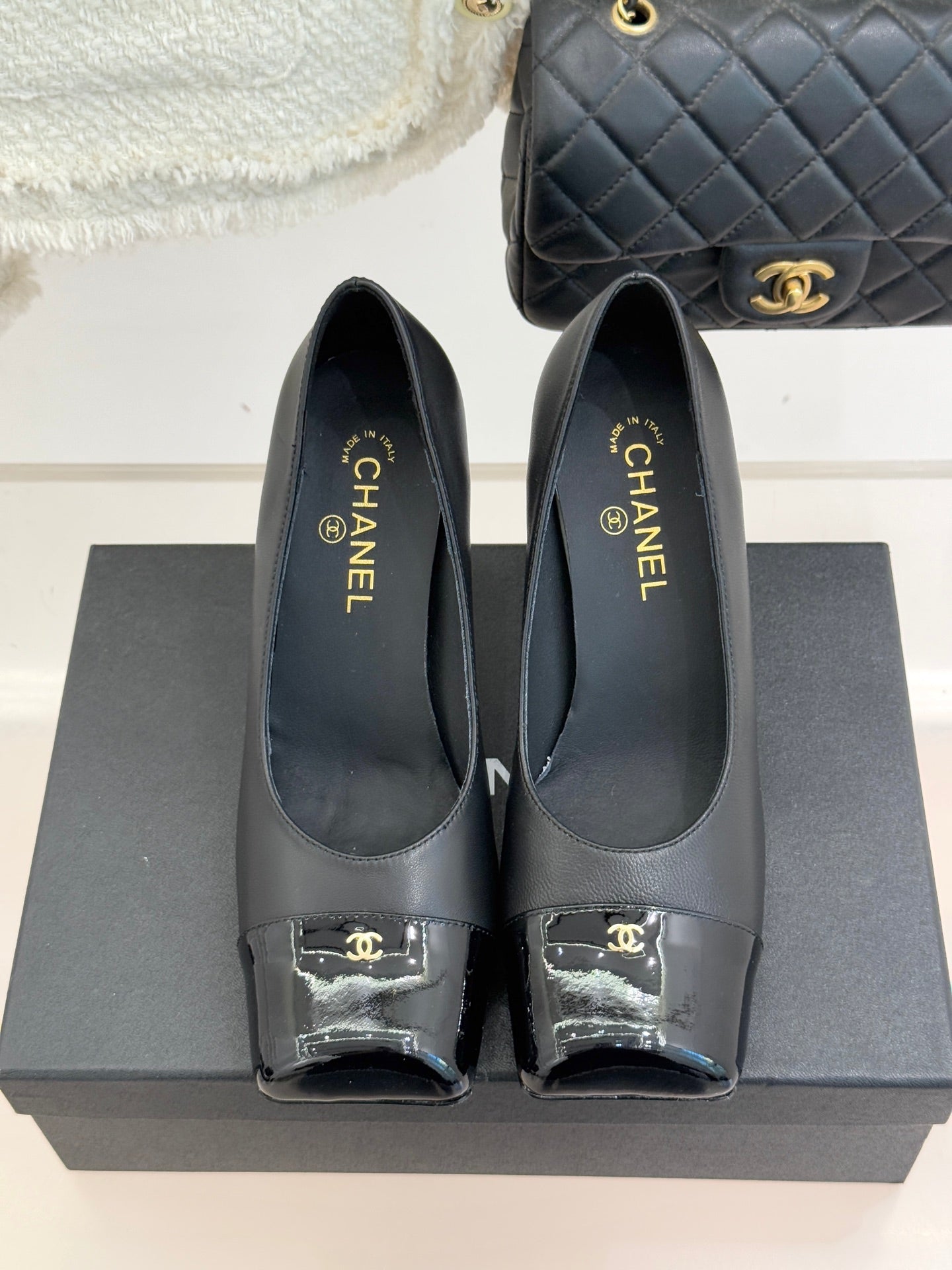 Black Chanel leather pumps, closed toe with patent trim and gold “CHANEL” branding