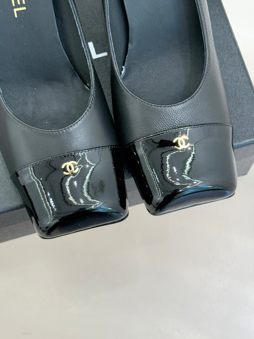 Black Chanel pumps close-up, glossy patent toe cap with gold Chanel logo