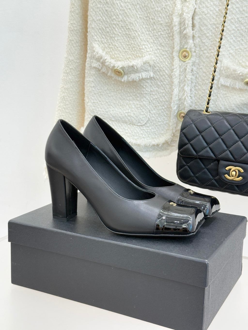 Black leather Chanel pumps with chunky heel and patent toe cap, gold logo detail