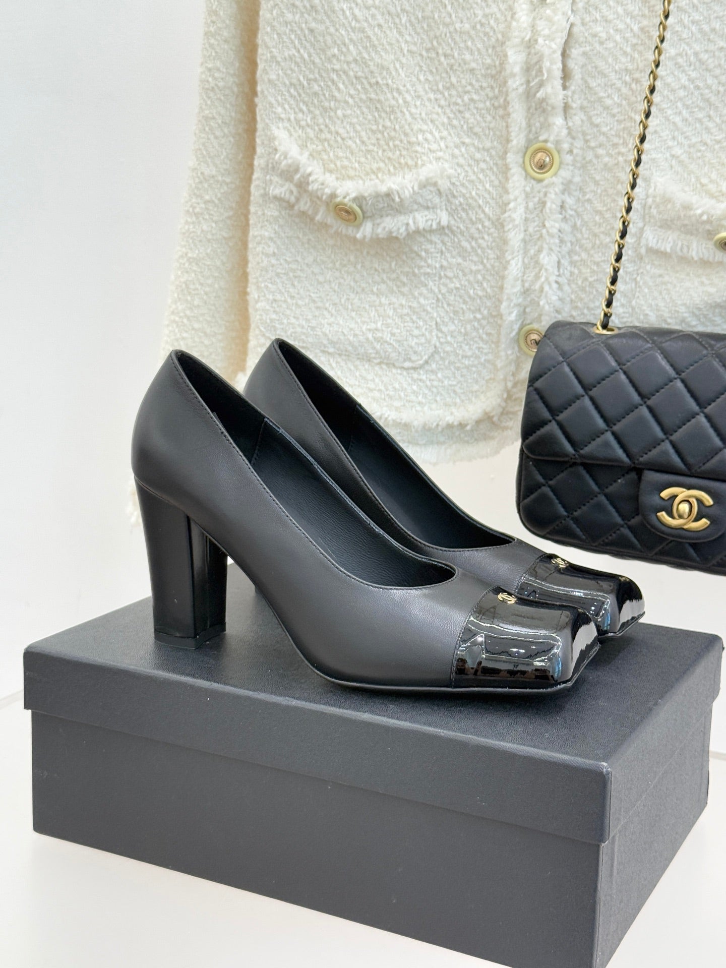 Black leather Chanel pumps with chunky heel and patent toe cap, gold logo detail