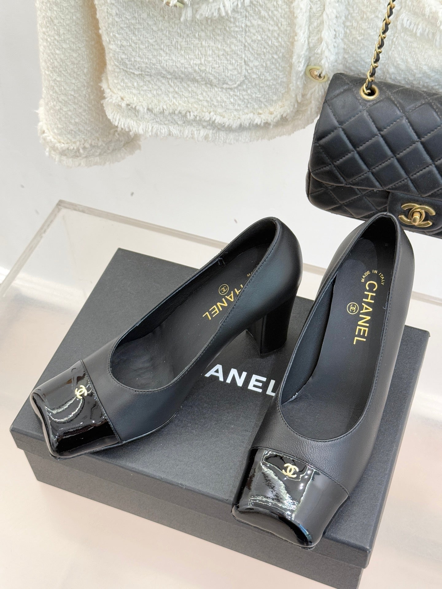 Black Chanel high-heel pumps with pointed toe, glossy patent toe caps and gold logos