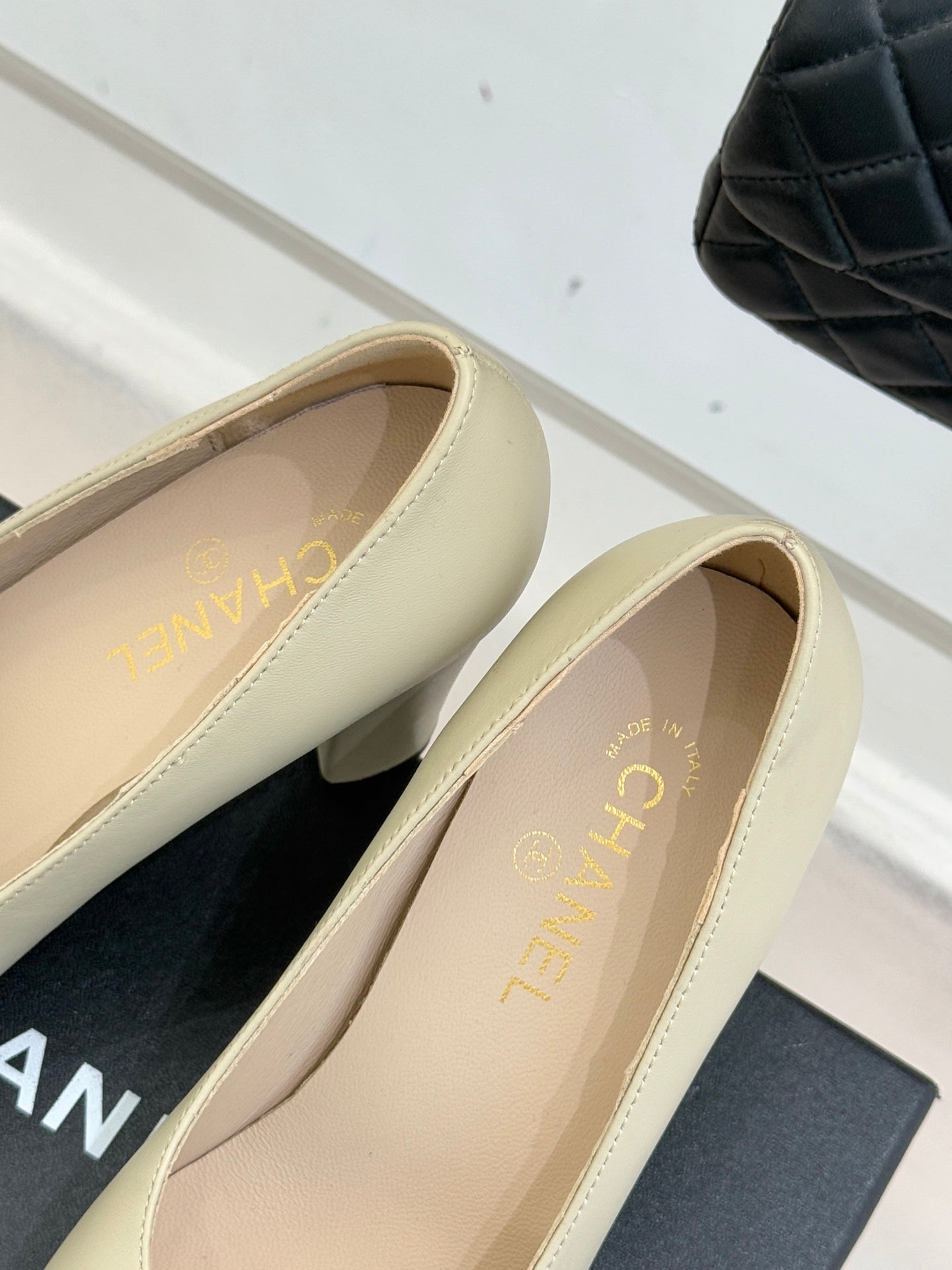 Beige pumps with gold logo on insole and black patent toe strap