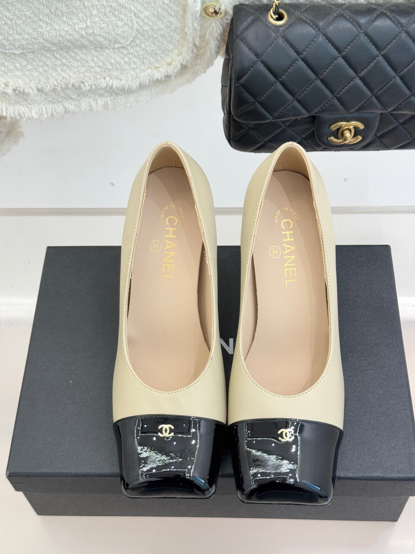 Beige pumps with black patent toe straps and gold CC emblem, back view