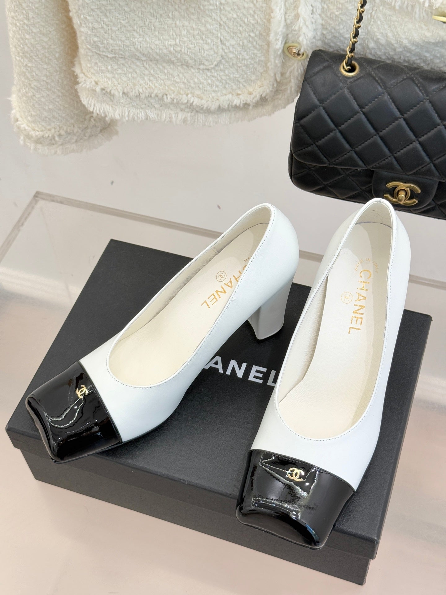 Women’s Chanel white pumps on display with black patent toe trim and heels