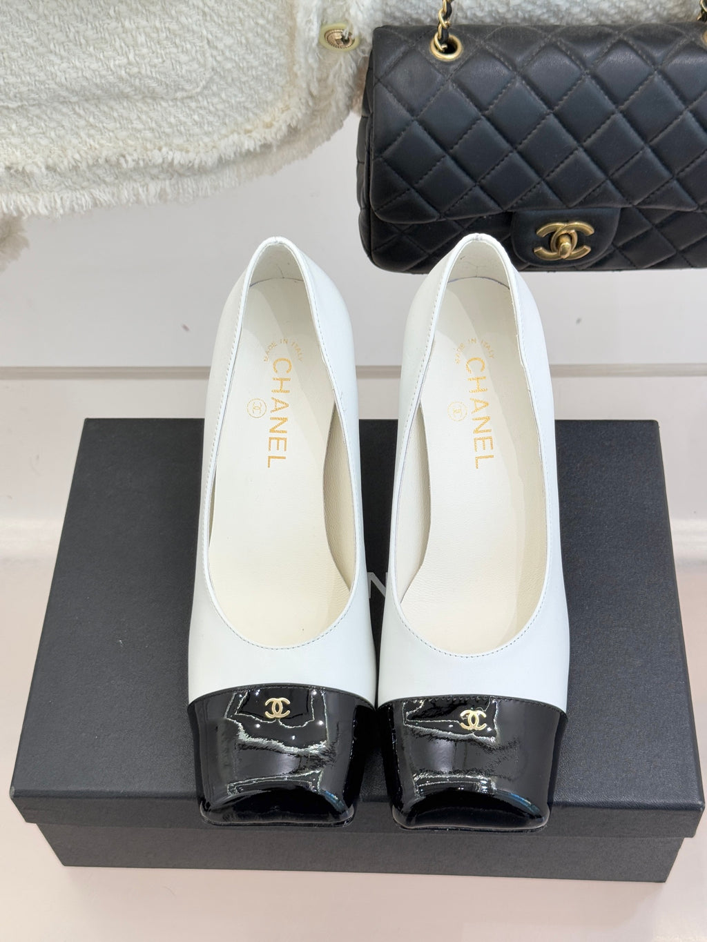 Women’s Chanel white pumps with black patent toe caps and curved heel profile