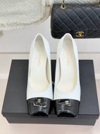 Women’s Chanel white pumps with black patent toe caps and curved heel profile