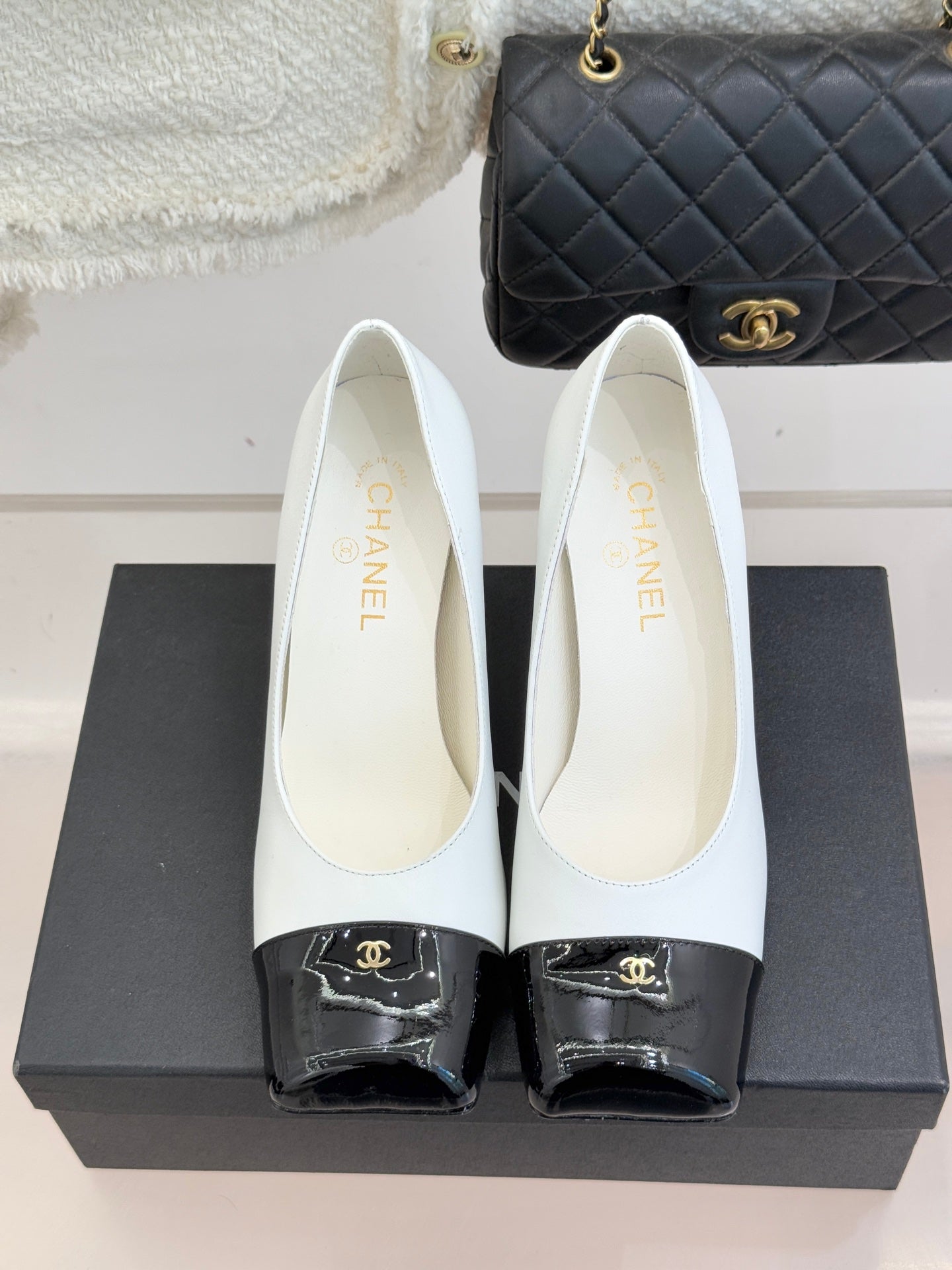 Women’s Chanel white pumps with black patent toe caps and curved heel profile