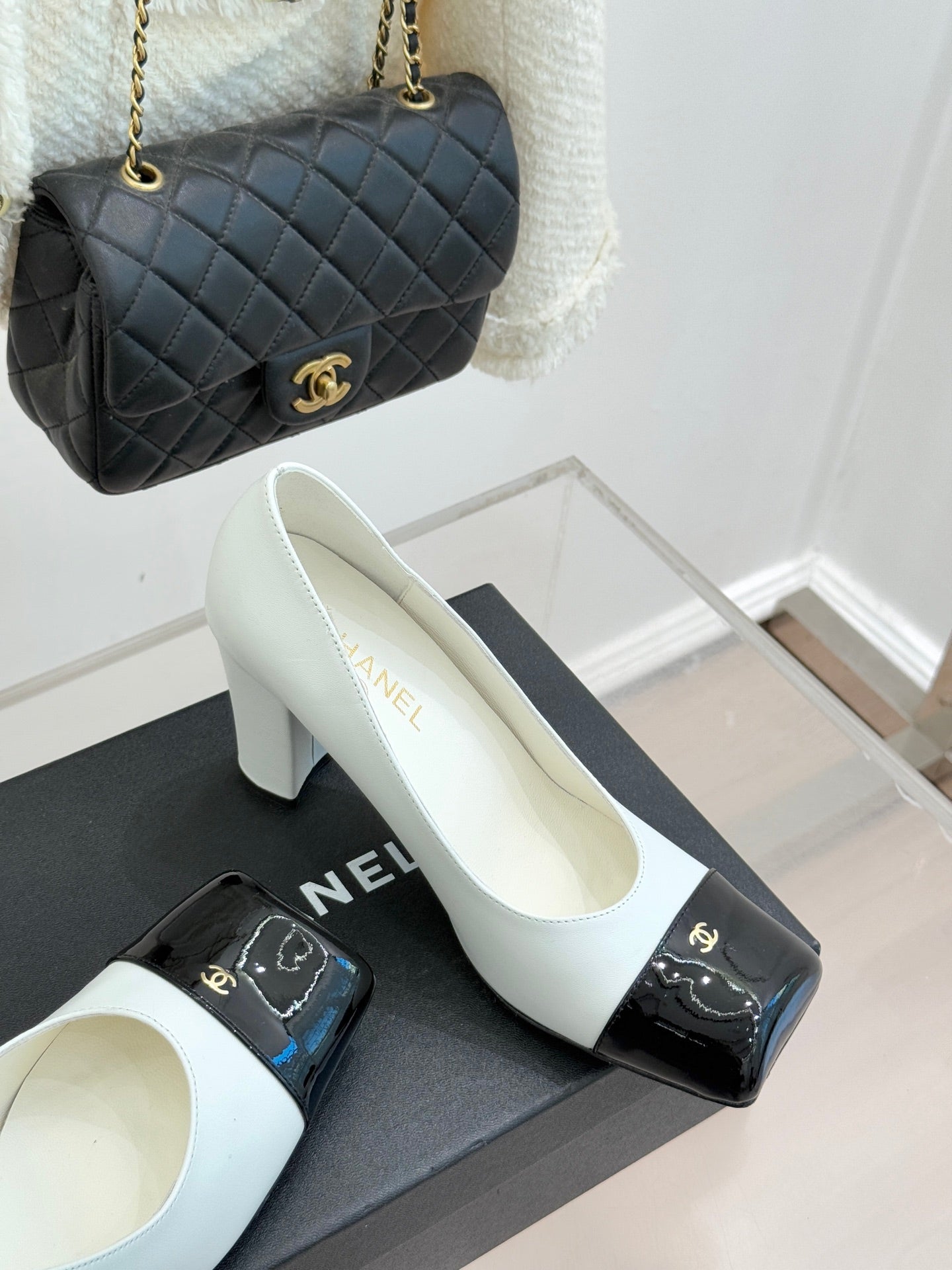 Women’s Chanel white pumps with black patent toe caps and chunky block heel