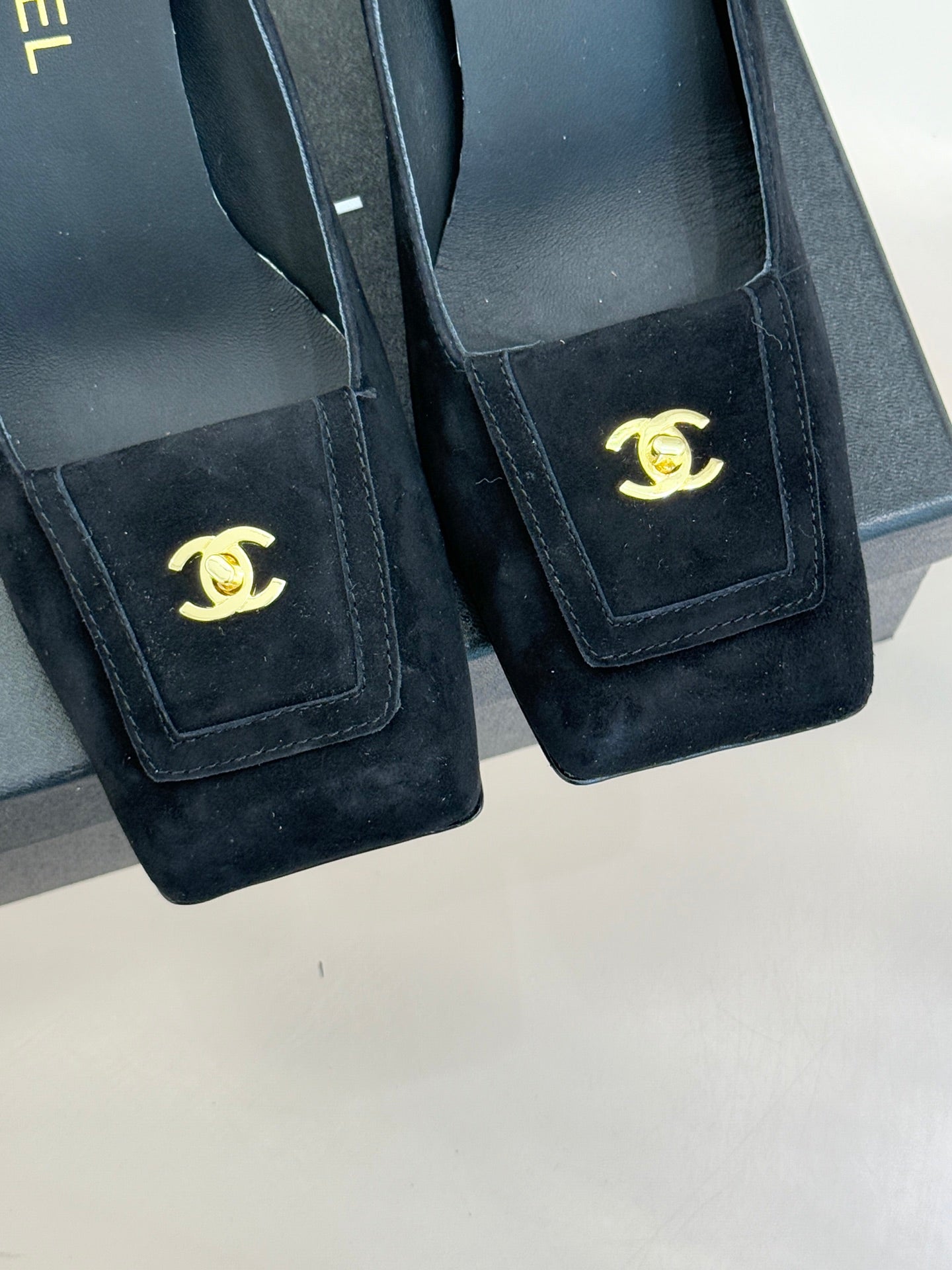 Black suede heeled loafers with gold CC emblem on front rectangular patch