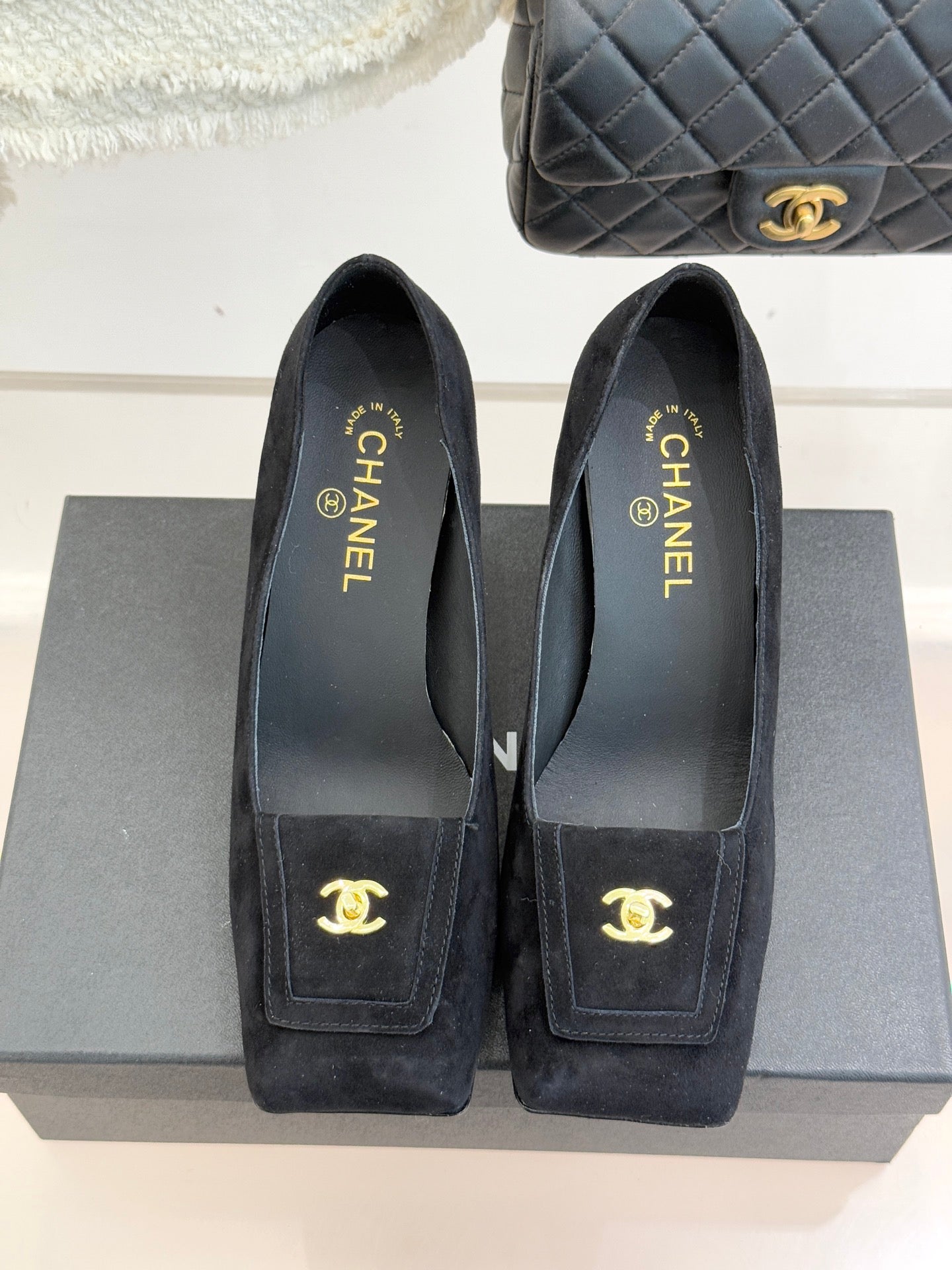 Black suede pointed-toe shoes with gold CC emblem on front patch