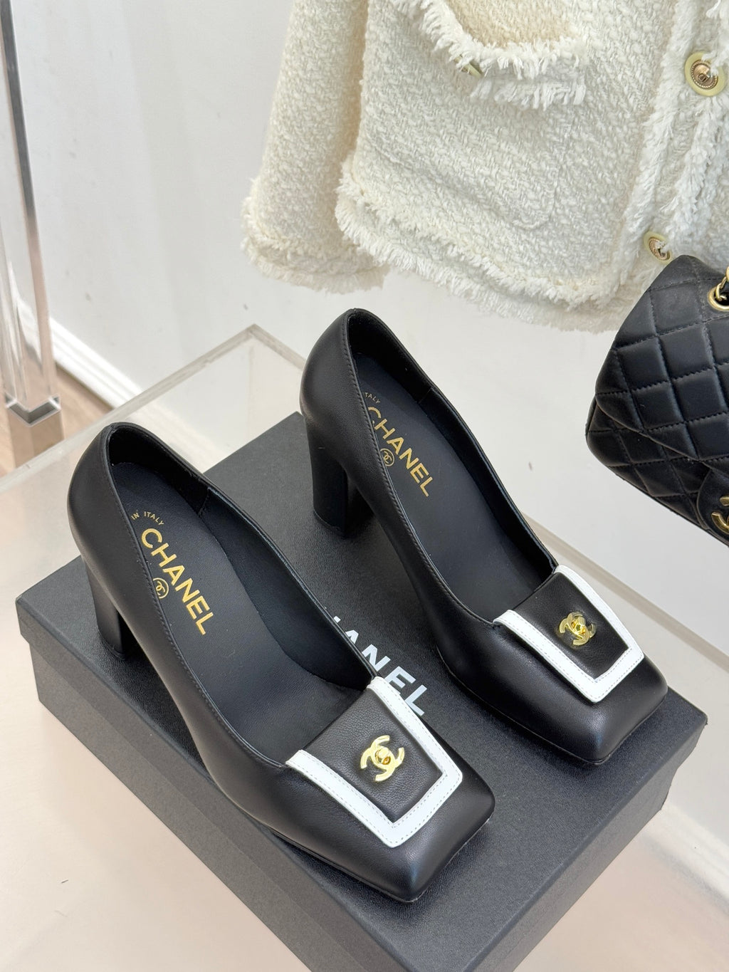 Pair of black heeled mules with white-trim buckle and gold CHANEL logo