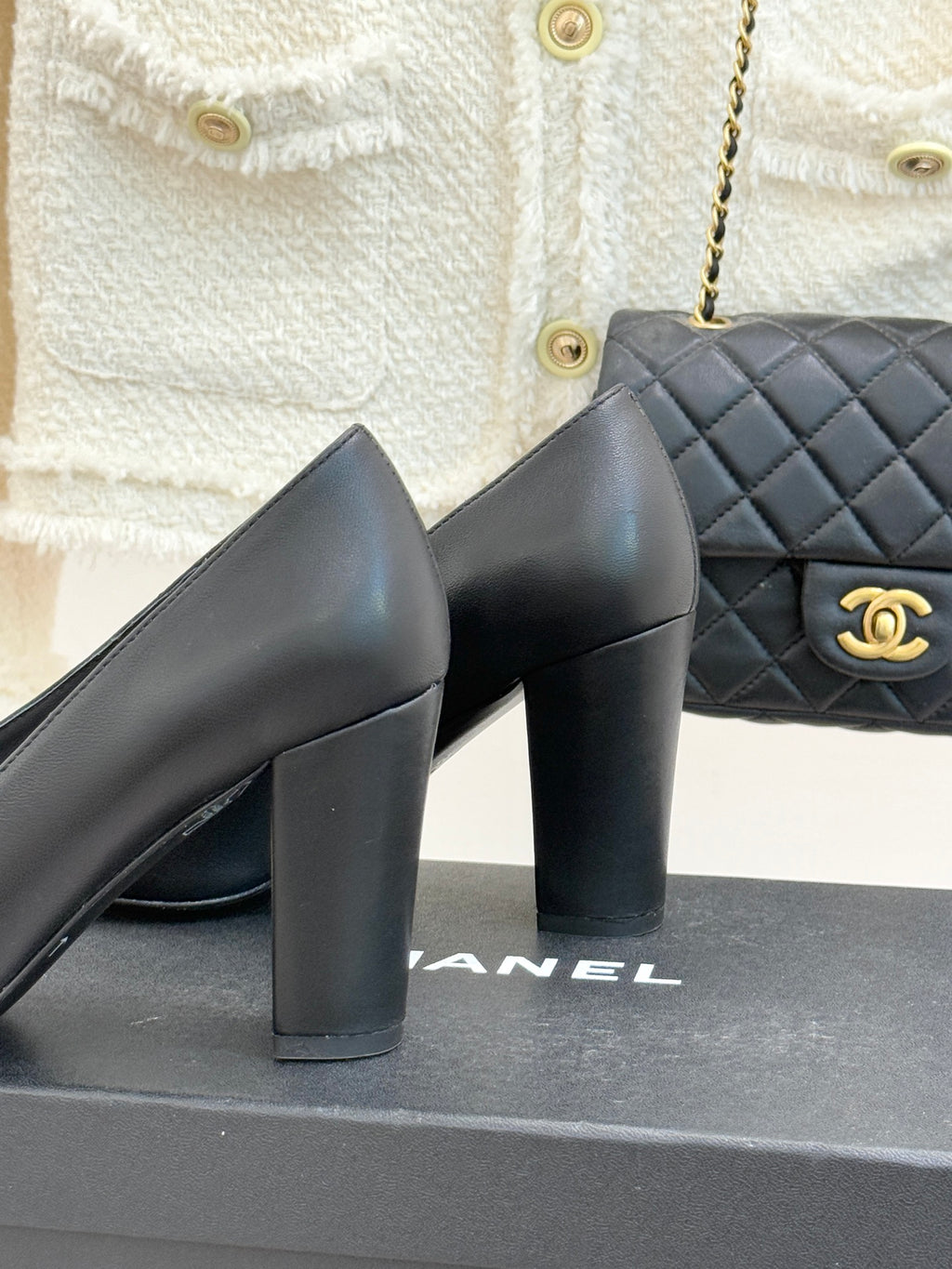 Black heeled mules, close side view, with white-trim buckle and gold logo