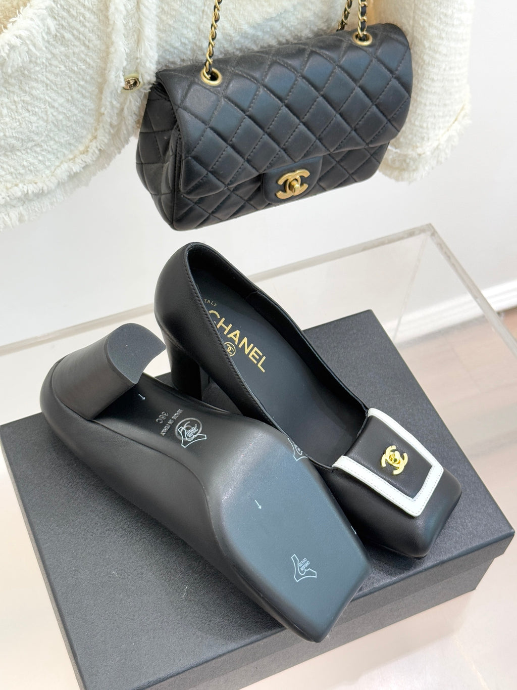 Black heeled mules with white-trim buckle and gold CC emblem, on box
