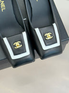 Black heeled mules close-up of white-trim buckle with gold CC emblem