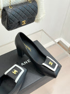 Black heeled mules on display with white-trim buckle and gold CC emblem