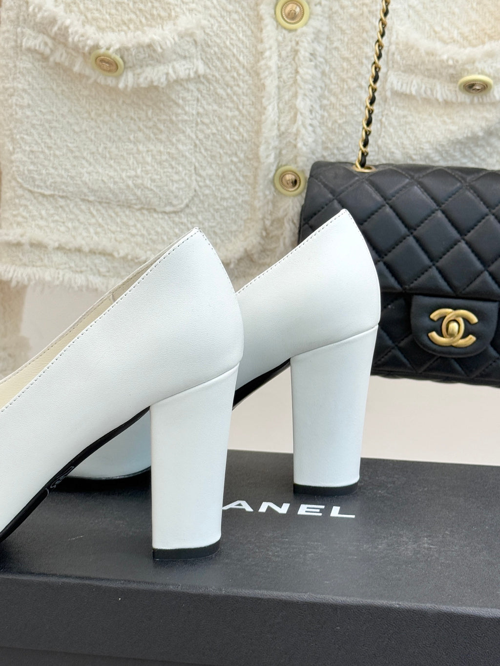 White leather block-heel pumps, side view, with gold logo on black-trimmed vamp