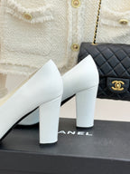 White leather block-heel pumps, side view, with gold logo on black-trimmed vamp