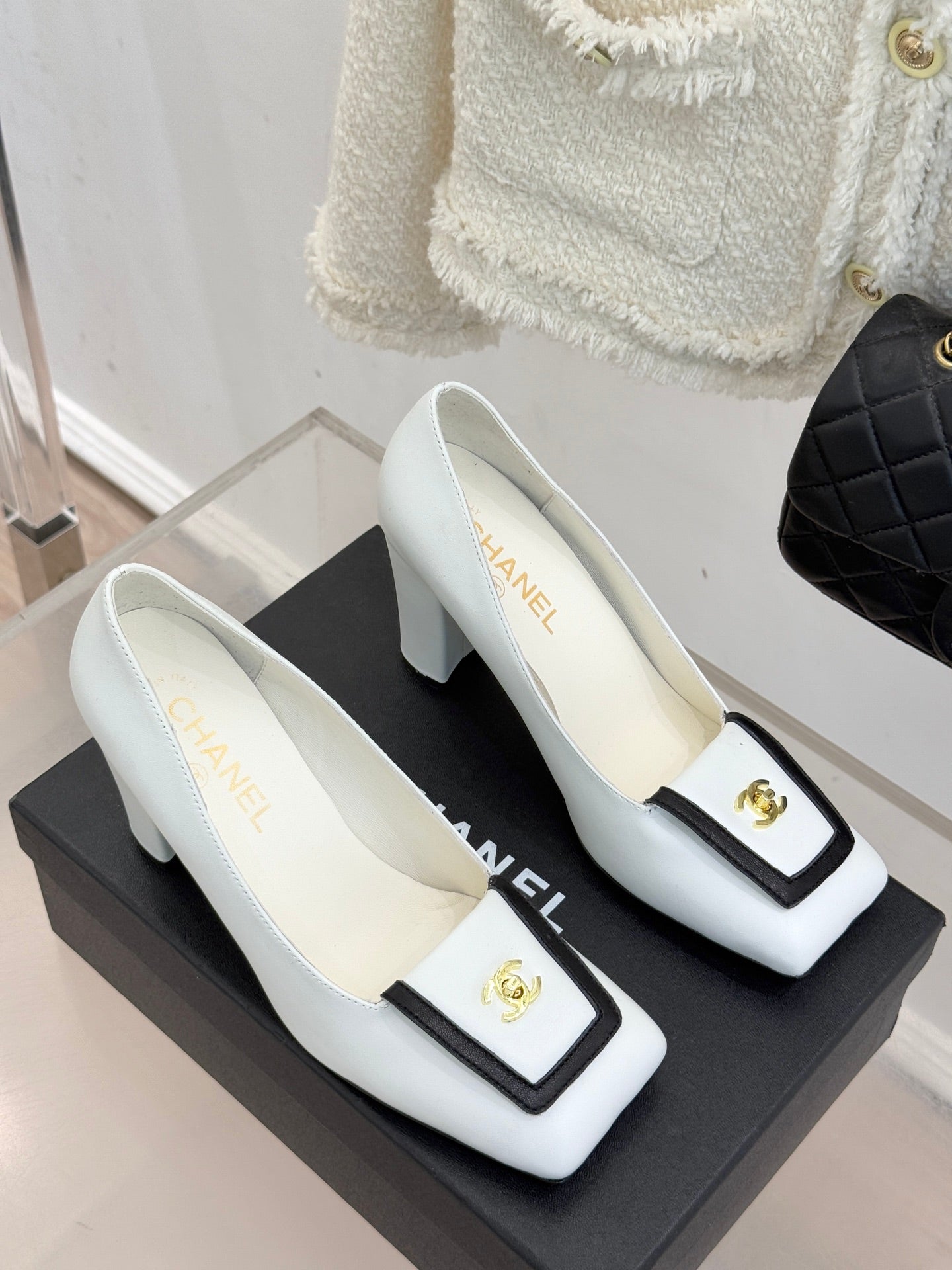 White leather block-heel pumps with black-trimmed toe and gold logo emblem