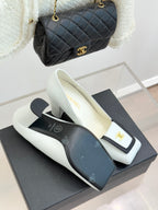 White leather block-heel pumps with black-trimmed front and gold logo on vamp