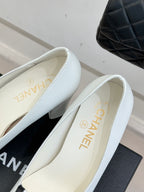 White leather pumps with gold CHANEL branding on insole and low block heel