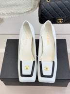 Pair of white leather block-heel pumps with gold logo on front and insoles